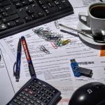 laptop, keyboard mouse and documents on desk