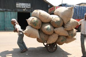 small man pulling enormous load of sacks